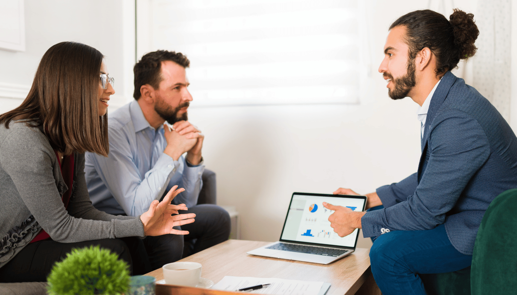 three people sitting around a table with a laptop
