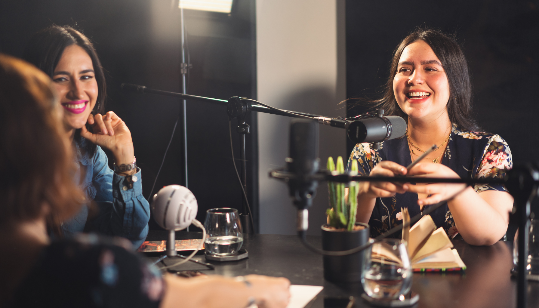 Two women smiling and speaking into microphones