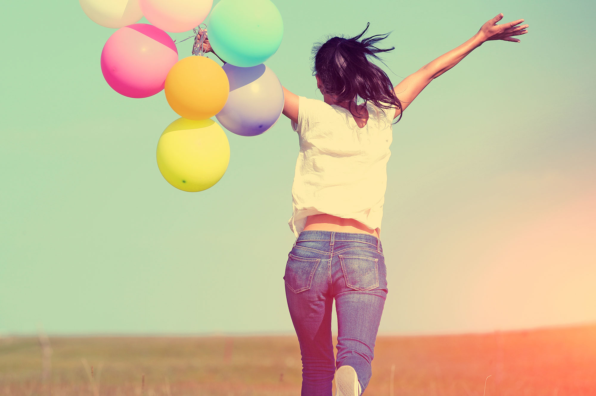 Person running through field with balloons