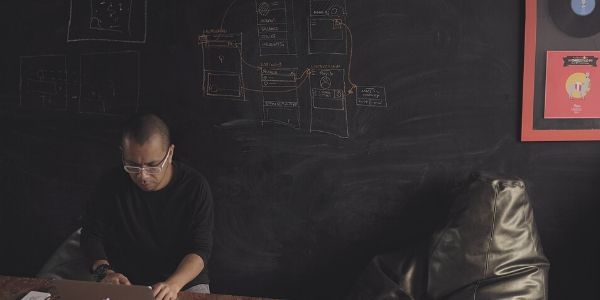 man-working-on-a-laptop-in-front-of-a-blackboard