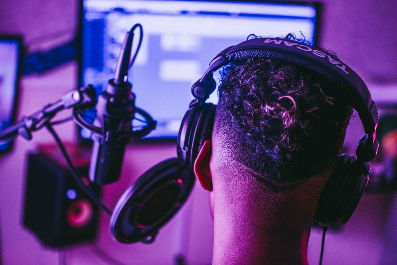 Person wearing headphones infront of screen with a mic